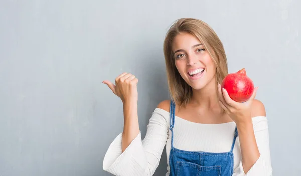 Schöne Junge Frau Über Grunge Graue Wand Mit Granatapfel Zeigt — Stockfoto