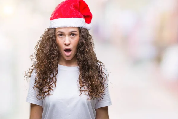年轻的黑发女孩戴着圣诞帽在孤立的背景恐惧和震惊与惊喜的表情 恐惧和兴奋的脸 — 图库照片
