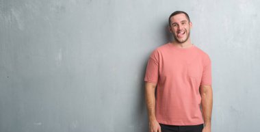 Beyaz delikanlı dilini gri grunge duvarın üzerinden out komik ifade ile mutlu. Duygu kavramı.