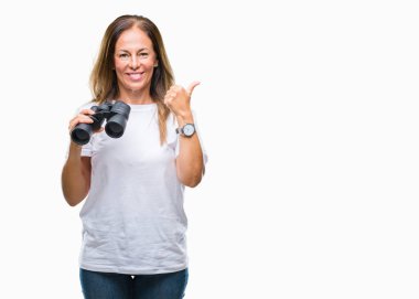 Orta yaş İspanyol kadın işaret ve başparmak kadar mutlu yüz gülümseyen tarafı ile gösteren izole arka plan üzerinde dürbün arıyor