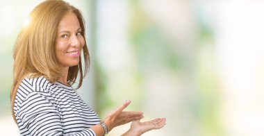 Açık el ile doğal gülümseyen girmek için davet izole arka plan üzerinde kazak giyen güzel orta yaş kadın çizgili