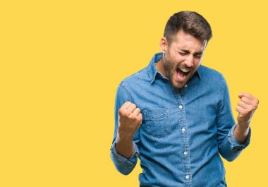 Soyutlanmış, mutlu ve heyecanlı genç bir adam kollarını kaldırmış, gülümseyen ve başarı için çığlık atan kazanan bir jest yapıyor. Kutlama konsepti.