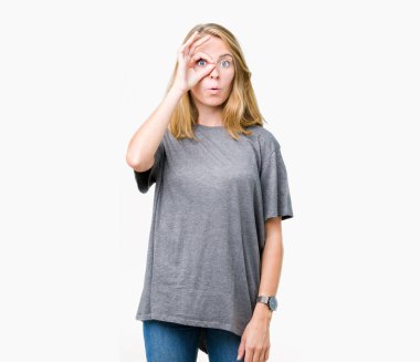 Sürpriz yüz, göz parmaklarının arasından seyir ile ok jest yapıyor izole arka plan üzerinde büyük boy rahat t-shirt giyen güzel genç kadın şok. İmansız ifade.