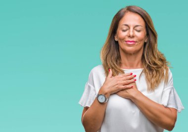 Orta yaş ile gülümseyen izole arka plan üzerine İspanyol kadın kıdemli kapalı gözler ve yüzünde minnettar jest ile göğüs üzerinde eller. Sağlık kavramı.