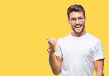 Seyir ve başparmak yanında yukarıyı mutlu yüz ile gülümseyen izole arka plan üzerinde gözlük takan genç yakışıklı adam.