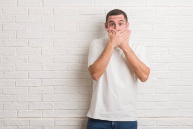 Beyaz tuğla duvar eller için hata ile ağız kapsayan şok üzerinde duran beyaz delikanlı. Gizli kavramı.
