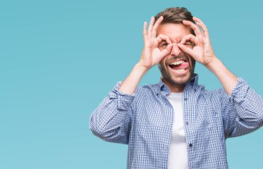 Dilini, parmaklarının arasından baktığını yapışmasını dürbün gibi ok jest yapıyor izole arka plan üzerinde beyaz t-shirt giyen genç yakışıklı adam. Deli ifade.