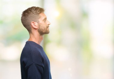 Genç yakışıklı adam giyen kış kazak izole arka tarafına, seyir üzerinde dinlenmek doğal yüz emin gülümseme ile pozuyla profili.