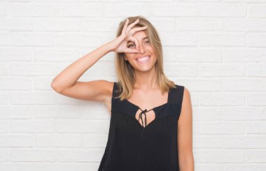 Beyaz tuğla duvar ile mutlu yüz el parmaklarının arasından seyir göz üzerinde ok işaretiyle yapıyor gülümseyen güzel genç kadın