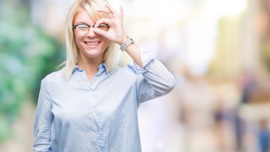 Gülümseyen, parmakları ile mutlu yüz üzerinden seyir göz el ile ok jest yapıyor izole arka plan üzerinde gözlük takan genç güzel sarışın iş kadını.