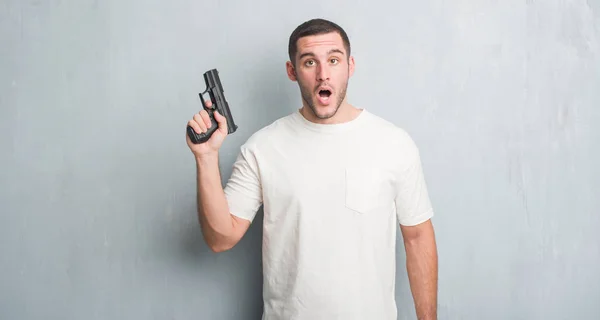 Gri Grunge Duvar Holding Silah Bir Sürpriz Yüz Korkuyor Heyecanlı — Stok fotoğraf