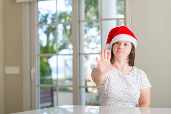 唐氏综合症妇女在家戴着圣诞帽 张开手做停止标志 用严肃而自信的表情 防御姿态 — 图库照片