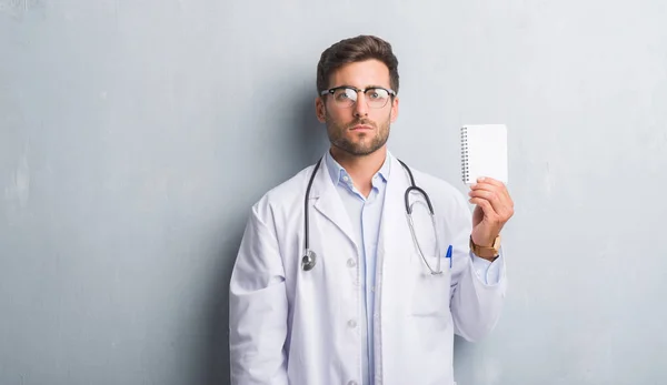 Bonito Jovem Médico Homem Sobre Parede Grunge Cinza Segurando Notebook — Fotografia de Stock