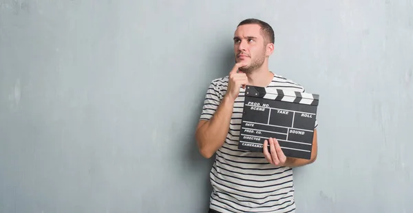 Junger Kaukasischer Mann Über Graue Grunge Wand Mit Filmklapptafel Ernstes — Stockfoto