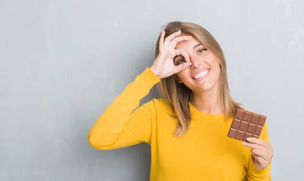 Schöne Junge Frau Über Grunge Grey Wall Eating Chocolate Bar — Stockfoto