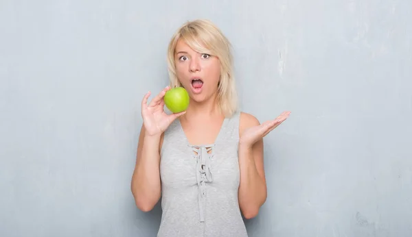 Mujer Caucásica Adulta Sobre Pared Gris Grunge Comiendo Manzana Verde — Foto de Stock