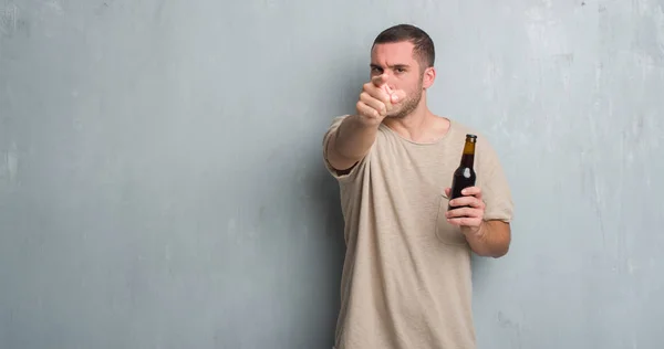 Kaukasische Jongeman Grijs Grunge Muur Fles Bier Met Vinger Wijzen — Stockfoto