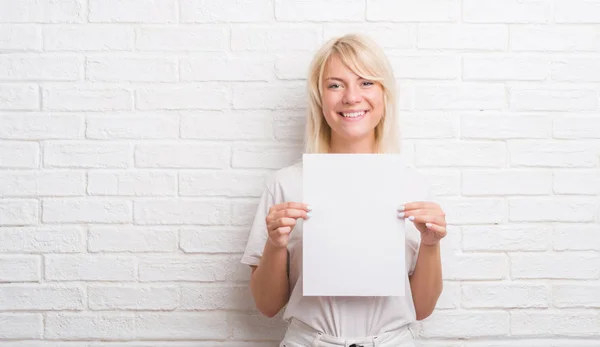 Mujer Caucásica Adulta Sobre Pared Ladrillo Blanco Sosteniendo Hoja Papel —  Fotos de Stock