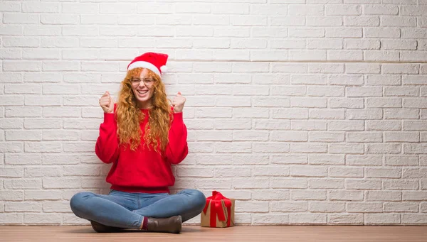 Young Redhead Woman Sitting Brick Wall Wearing Christmas Hat Excited — Stock Photo, Image
