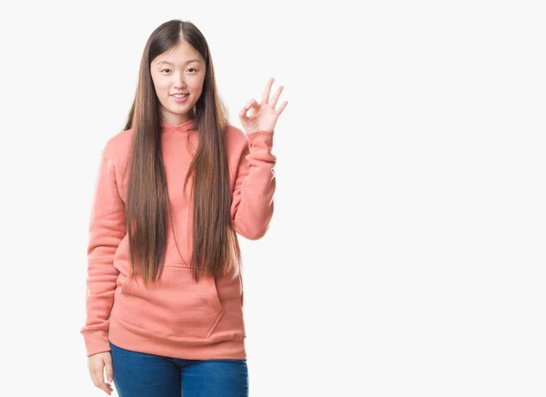 孤立した背景着てスポーツ Sweathshirt を浮かべて上手と指で サインをしている肯定的な若い中国の女性 成功した式 — ストック写真