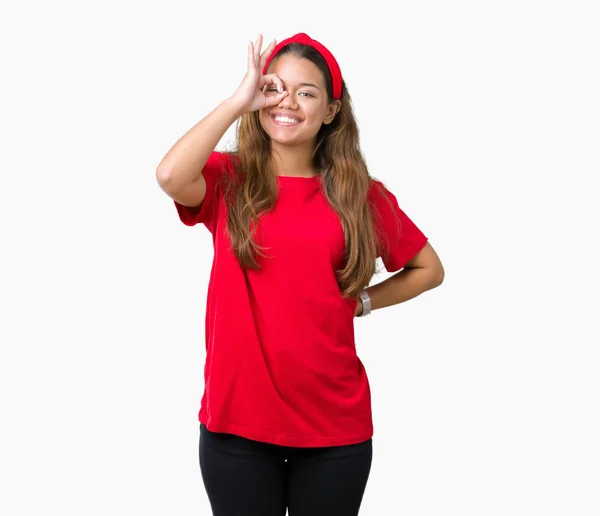 年轻美丽的黑发女人穿着红色的 T恤在孤立的背景做确定的手势与手微笑 眼睛通过手指看与快乐的脸 — 图库照片
