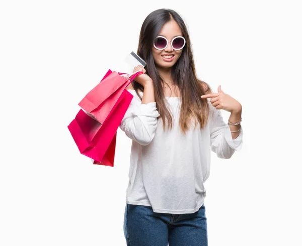自分自身に驚き顔ポインティング指で孤立した背景の上販売の買い物袋を保持している若いアジア女性 — ストック写真
