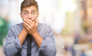 Genç yakışıklı iş adamı izole arka plan ağız hata için elleriyle kapsayan şok içinde. Gizli kavramı.