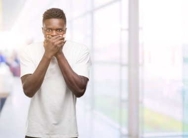 Beyaz t-shirt ağız hata için elleriyle kapsayan şok giyen genç Afro-Amerikan adam. Gizli kavramı.