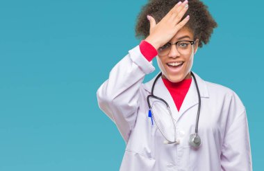 Young afro american doctor woman over isolated background surprised with hand on head for mistake, remember error. Forgot, bad memory concept. clipart