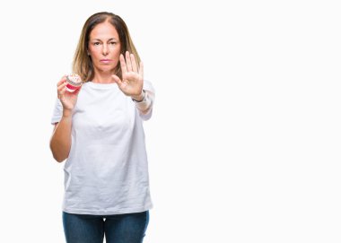 Orta yaş İspanyol kadın açık eliyle dur işareti ile ciddi ve kendine güvenen ifade, savunma jest yapıyor izole arka plan üzerinde kek yeme
