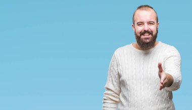 Üzerinde kış kazak giyen genç beyaz hipster adam arka plan dostu sunan karşılıklı tebrik ve davet edici gülümseyen izole. Başarılı iş.