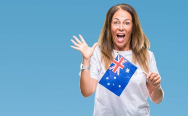 Avustralya bayrağı tutan orta yaş İspanyol kadın büyük gülümseme ile çığlık zaferini kutluyor ve ellerini kaldırdı arka plan çok mutlu ve heyecanlı, kazanan ifade izole