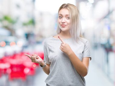 Sarışın genç kadın gülümseyerek ve iki elleri ve parmakları ile tarafına işaret kamera bakarak izole arka plan üzerinde.