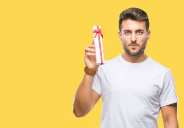 Acımak yüz ciddi düşünüyorum üstünde kendine güvenen bir ifade ile izole arka plan üzerinde Sevgililer günü hediyesi veren aşık genç yakışıklı adam