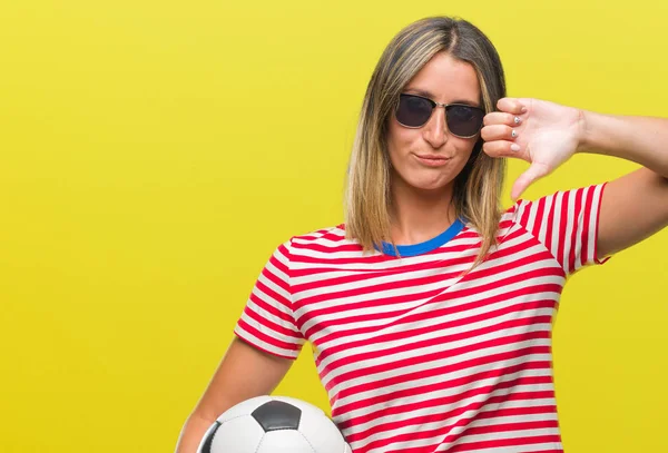 Kızgın yüz, eksi işareti aşağı antipati başparmak ile gösterilen, ret kavramı ile izole arka plan üzerinde futbol futbol topu tutan genç güzel kadın