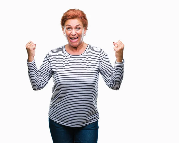 Atrractive üst düzey beyaz Kızıl saçlı kadın kutluyor izole arka plan üzerinde şaşırttı ve başarı için kaldırdı kollarını açarak hayret ve gözleri açık. Kazanan kavramı.