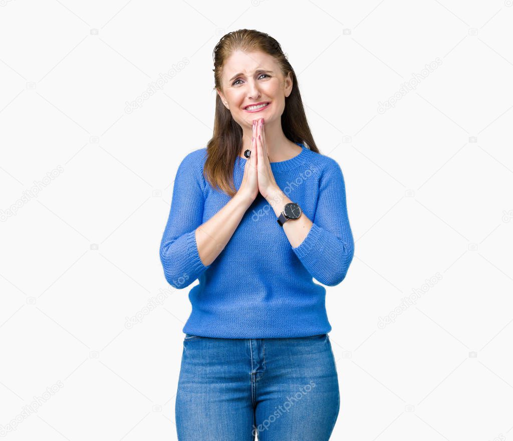 Beautiful middle age mature woman wearing winter sweater over isolated background praying with hands together asking for forgiveness smiling confident.