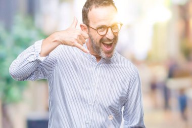 Orta yaş ağarmış komuta sizde yapıyor gülümseyen izole arka plan üzerinde gözlük telefon hareketi ile el ve parmak telefonda konuşuyor gibi. Kavramları iletişim.