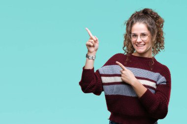 Güzel esmer kıvırcık saçlı Genç kız gülümseyerek ve iki elleri ve parmakları ile tarafına işaret kamera bakarak izole arka plan üzerinde gözlük.