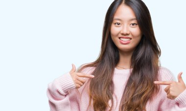 Yüzünde gülümseme ile kendinden emin görünüyorsun, kendini gururlu ve mutlu parmakları ile işaret izole arka plan üzerinde Genç Asyalı kadın.