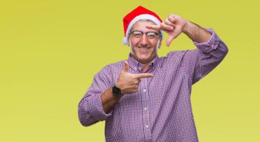 Elle yapma çerçeve ve parmakları ile mutlu yüz gülümseyen izole arka plan üzerinde Noel şapka giymiş yakışıklı komuta sizde. Yaratıcılık ve Fotoğrafçılık kavramı.