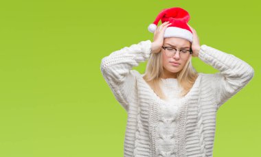 Çünkü çaresiz ve stresli baş ağrısı acı izole arka plan üzerinde Noel şapka giyen genç beyaz kadın ağrı ve migren. Ellerini kafasına.