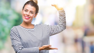 Genç güzel kadın rahat kazak ile büyük ve büyük boy işaret, ölçü birimi sembol gösteren el eller izole arka plan üzerinde çizgili. Kameraya bakarak gülümsüyordu. Ölçüm kavramı.