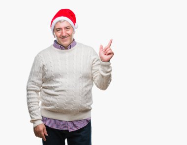 Kameraya bakarak yan el ve parmak ile işaret eden yakışıklı komuta sizde yüzünde kocaman bir gülümseme ile izole arka plan üzerinde Noel şapka.