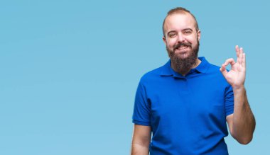 İzole arka plan el ve parmaklar ok işaretiyle yapıyor olumlu gülümseyen üzerinde mavi gömlek giyen genç beyaz hipster adam. Başarılı ifade.