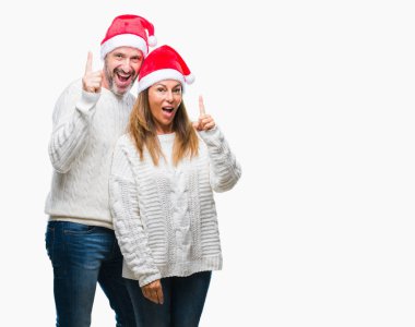 Orta yaş İspanyol çift başarılı fikirle izole arka plan işaret parmağı üzerinde Noel şapka takıyor. Çıktıktan ve mutlu. Bir numara.