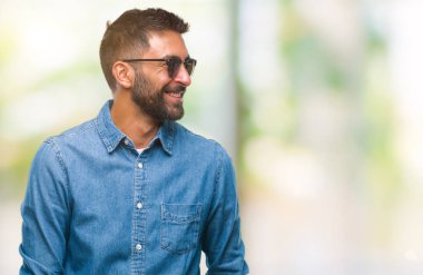 Yetişkin İspanyol adam uzak tarafına yüzünde, doğal ifade gülümseme ile seyir izole arka plan üzerinde güneş gözlüğü takıyor. Kendine güvenen gülüyor.