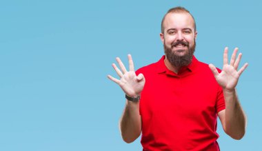 Gösterilen arka plan üzerinde kırmızı gömlek giyen genç beyaz hipster adam izole ve parmakları ile işaret numara 9 kendinden emin ve mutlu gülümseyerek süre.