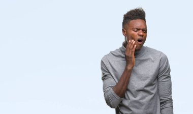 Afrikalı-Amerikalı genç diş ağrısı veya dişlerde dişlerle ilgili hastalık nedeniyle ağız acı ifadesi ile el ile dokunmak izole arka plan üzerinde. Diş hekimi kavramı.