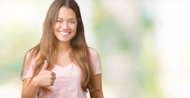 Hareketi el ile mutlu yaşasın yapıyor izole arka plan üzerinde pembe tişört giyen genç güzel esmer kadın. Kameraya bakarak başarı gösteren ile ifade onaylama.